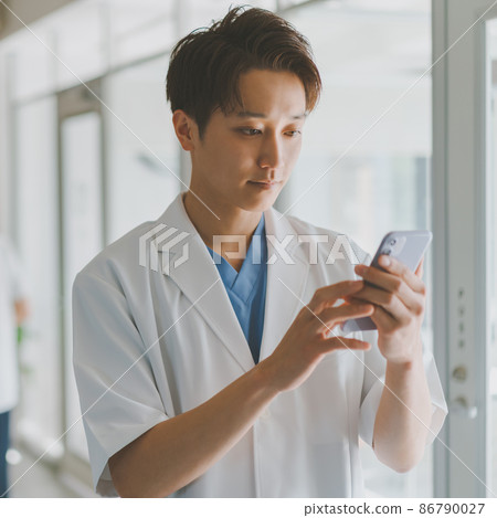 A man in a white coat and a smartphone A man in a white coat and a smartphone 86790027
