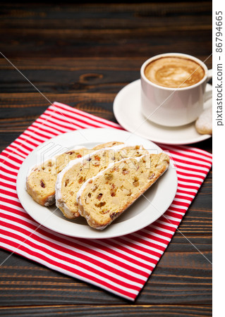 Slices of Traditional Christmas stollen cake with marzipan and dried fruit and cup of coffee 86794665