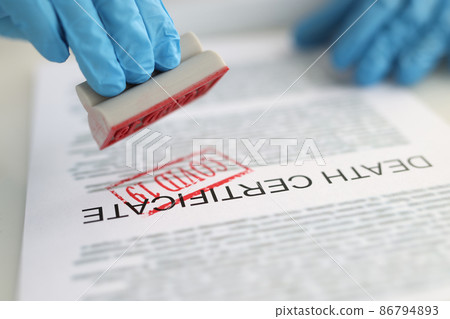 Pathologist putting red covid19 stamp on death certificate closeup Pathologist putting red covid19 stamp on death certificate closeup 86794893