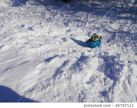 A child sledding on a sunny winter day (back view) A child sledding on a sunny winter day (back view) 86795522