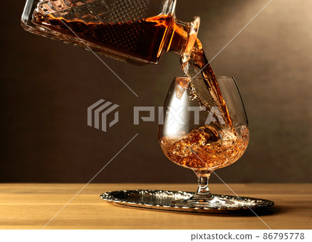 Brandy is poured into a snifter glass. Brandy is poured into a snifter glass. 86795778