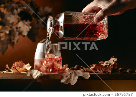 Whiskey is poured into a glass with ice. Whiskey is poured into a glass with ice. 86795787