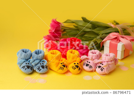 Pregnancy motherhood perenthood concept, Three pairs of baby booties on yellow background, baby shower, first birthday party banner, handmade socks, daycare, kindergarten, nursery, mother mom Pregnancy motherhood perenthood concept, Three pairs of baby booties on yellow background, baby shower, first birthday party banner, handmade socks, daycare, kindergarten, nursery, mother mom 86796471