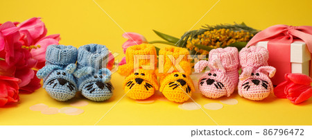 Pregnancy motherhood perenthood concept, Three pairs of baby booties on yellow background, baby shower, first birthday party banner, handmade socks, daycare, kindergarten, nursery, mother mom Pregnancy motherhood perenthood concept, Three pairs of baby booties on yellow background, baby shower, first birthday party banner, handmade socks, daycare, kindergarten, nursery, mother mom 86796472