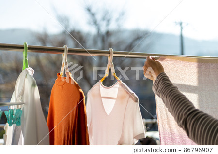 一個女人在陽台上曬衣服 86796907