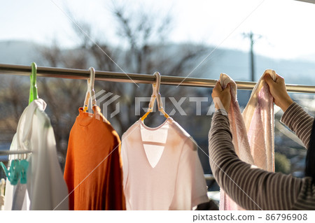 A woman is drying her laundry on the balcony A woman is drying her laundry on the balcony 86796908