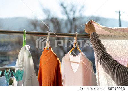 A woman is drying her laundry on the balcony A woman is drying her laundry on the balcony 86796910