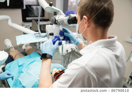 Dentist with dental microscope  86798618