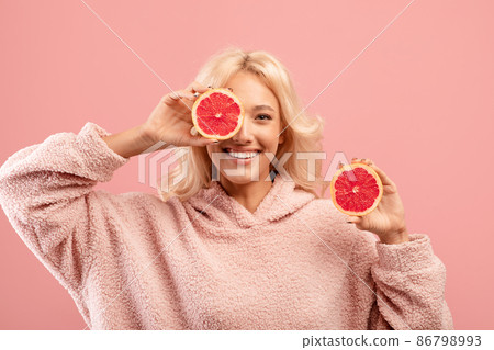 Vitamins for beauty and skin care. Happy caucasian lady posing with grapefruit halves on pink studio background 86798993