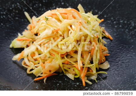 Pickled slices of cabbage and carrot on a plate, closeup view 86799859
