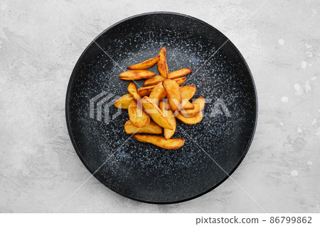 Garnish to the main dish - slices of potato wedges fried in oil, top view 86799862