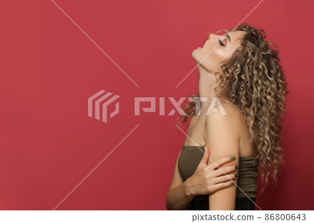 Portrait of fashion model with long curly hair on red Portrait of fashion model with long curly hair on red 86800643