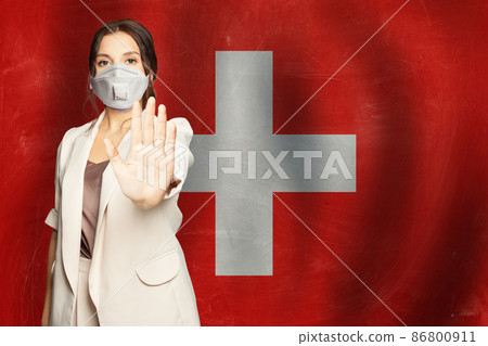 Smart successful woman in protective medical mask showing stop gesture on flag of Switzerland  86800911