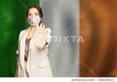 Young woman in protective medical mask showing stop gesture on flag of Ireland background 86800921