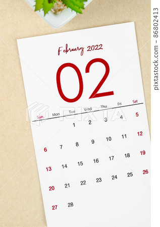 February 2022 calendar with plant pot on brown paper background. 86802413