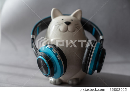 Black and turquoise headphones and piggy bank on a gray background. Wireless device for listening to music and communication. Black and turquoise headphones and piggy bank on a gray background. Wireless device for listening to music and communication. 86802925