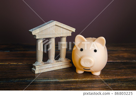 Piggy bank near the state building. Savings deposit in the bank. Use of investment instruments to increase funds, reduce inflationary risks. Budget. Tax collection. Financial system, commerce 86803225