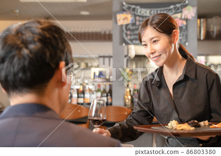 Female staff and male guests serving wine 86803380