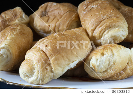 Sweet croissants in a plate on the table 86803813