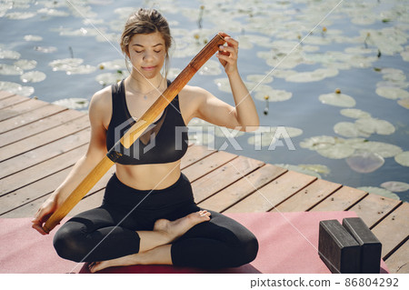 Woman practicing advanced yoga by the water 86804292