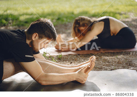 Man and woman doing yoga exercises in the park Man and woman doing yoga exercises in the park 86804338