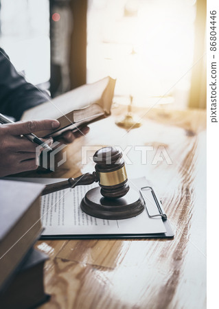 Focus at wooden gavel with lawyer reading book of law, vertical image. 86804446