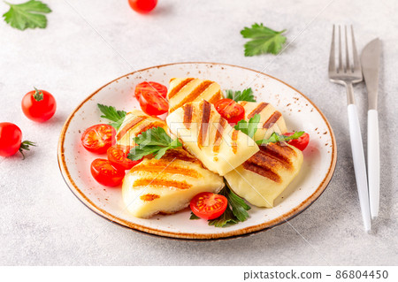 Grilled halloumi cheese served with tomatoes and parsley 86804450