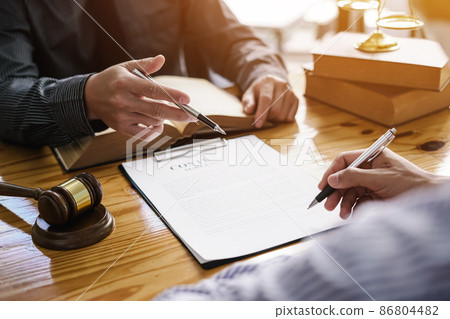 Attorneys provide legal and litigation advice to clients, businessman holding pen and pointing to contract paper. Attorneys provide legal and litigation advice to clients, businessman holding pen and pointing to contract paper. 86804482