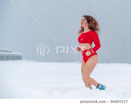 Caucasian woman dressed in shorts and top jogging in winter. Caucasian woman dressed in shorts and top jogging in winter. 86805527