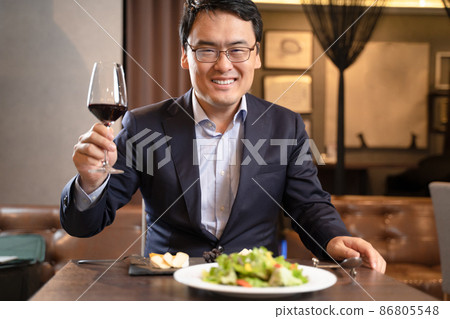 A man toasting with red wine at a restaurant 86805548