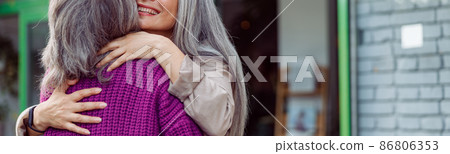 Senior Asian woman hugs friend meeting on modern city street 86806353