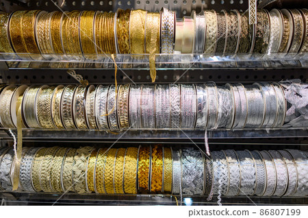 Gold and silver glitter ribbon roll on rack in DIY shop 86807199