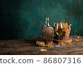 A glass of homemade white wine with grapes and a bottle on a rustic wooden table 86807316