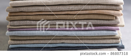 A pile of four folded dull-colored natural linen fabric 86807318