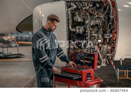 Male airline mechanic using tool box in hangar Male airline mechanic using tool box in hangar 86807464
