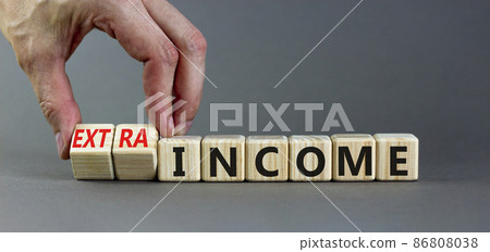 Extra income symbol. Businessman turns wooden cubes and changes concept words income to extra income. Beautiful grey table, grey background copy space. Business and extra income concept. Extra income symbol. Businessman turns wooden cubes and changes concept words income to extra income. Beautiful grey table, grey background copy space. Business and extra income concept. 86808038