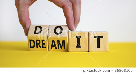 Dream and do it symbol. Businessman turns cubes and changes words 'dream it' to 'do it'. Beautiful yellow table, white background. Business and Dream and do it concept. Copy space. 86808103