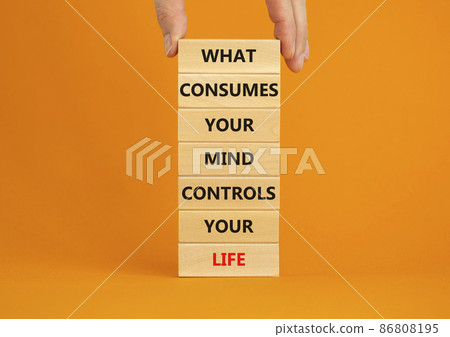 Motivational symbol. Wooden blocks with words What consumes your mind controls your life. Beautiful orange background, copy space. Businessman hand. Business, motivational lifestyle concept. Motivational symbol. Wooden blocks with words What consumes your mind controls your life. Beautiful orange background, copy space. Businessman hand. Business, motivational lifestyle concept. 86808195
