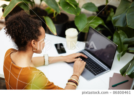 Young African American woman looking at laptop screen while typing on keyboard Young African American woman looking at laptop screen while typing on keyboard 86808461