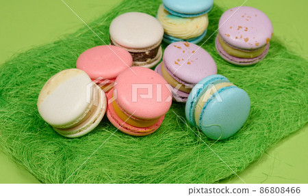 baked macarons with different flavors on a green background, top view baked macarons with different flavors on a green background, top view 86808466
