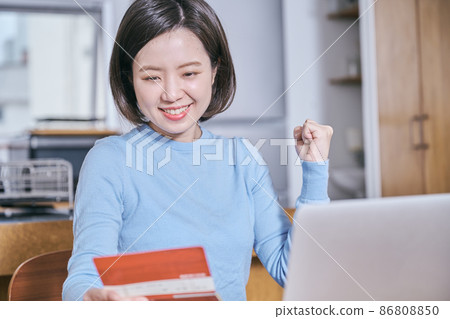 A young woman doing a guts pose looking at a bankbook 86808850