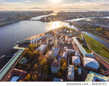 Russia, St. Petersburg, Aerial landscape of Peter and Paul cathedral at sunset, walls of fortress, Golden autumn, panorama landscape, golden spire with cross and angel, drawbridges, river Neva 86809143