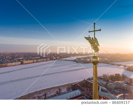Aerial view of golden Angel and Cross on spike of the Peter and Paul cathedral in Saint Petersburg at sunset, frozen Neva River, sunny frosty day, Winter Palace, Admiralty, Rostral columns Aerial view of golden Angel and Cross on spike of the Peter and Paul cathedral in Saint Petersburg at sunset, frozen Neva River, sunny frosty day, Winter Palace, Admiralty, Rostral columns 86809157