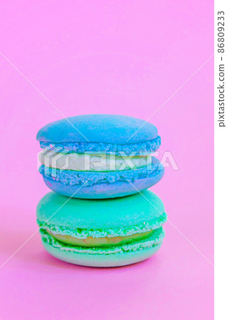Sweet almond colorful unicorn blue green macaron or macaroon dessert cake isolated on trendy pink pastel background. French sweet cookie. Minimal food bakery concept. Copy space Sweet almond colorful unicorn blue green macaron or macaroon dessert cake isolated on trendy pink pastel background. French sweet cookie. Minimal food bakery concept. Copy space 86809233