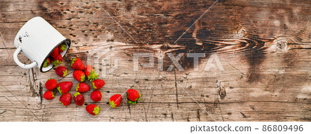 Strawberries on a wooden countertop, scattered from a mug. Strawberries on a wooden countertop, scattered from a mug. 86809496