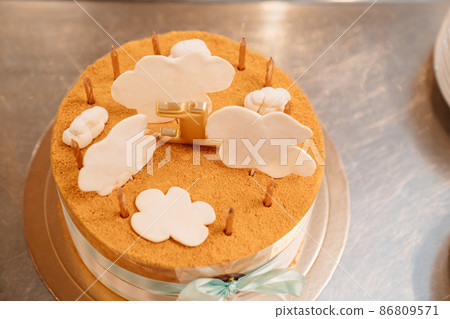 a small cake decorated with ribbons and sugar clouds with candles 86809571