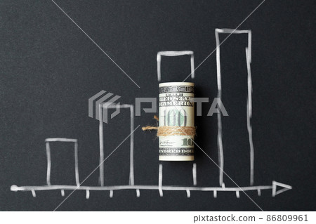 The concept of growth in business and increase in profits on a graph with a roll of money. The concept of growth in business and increase in profits on a graph with a roll of money. 86809961
