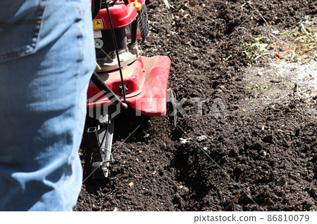 Cultivating garden soil in the spring with a rototiller 86810079