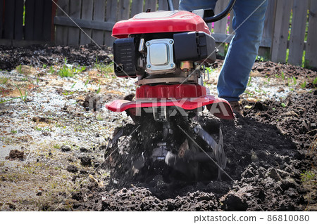 Cultivating garden soil in the spring with a rototiller 86810080