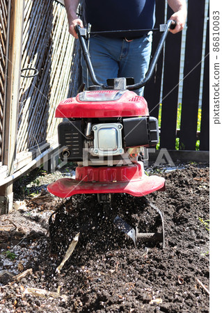 Cultivating garden soil in the spring with a rototiller 86810083